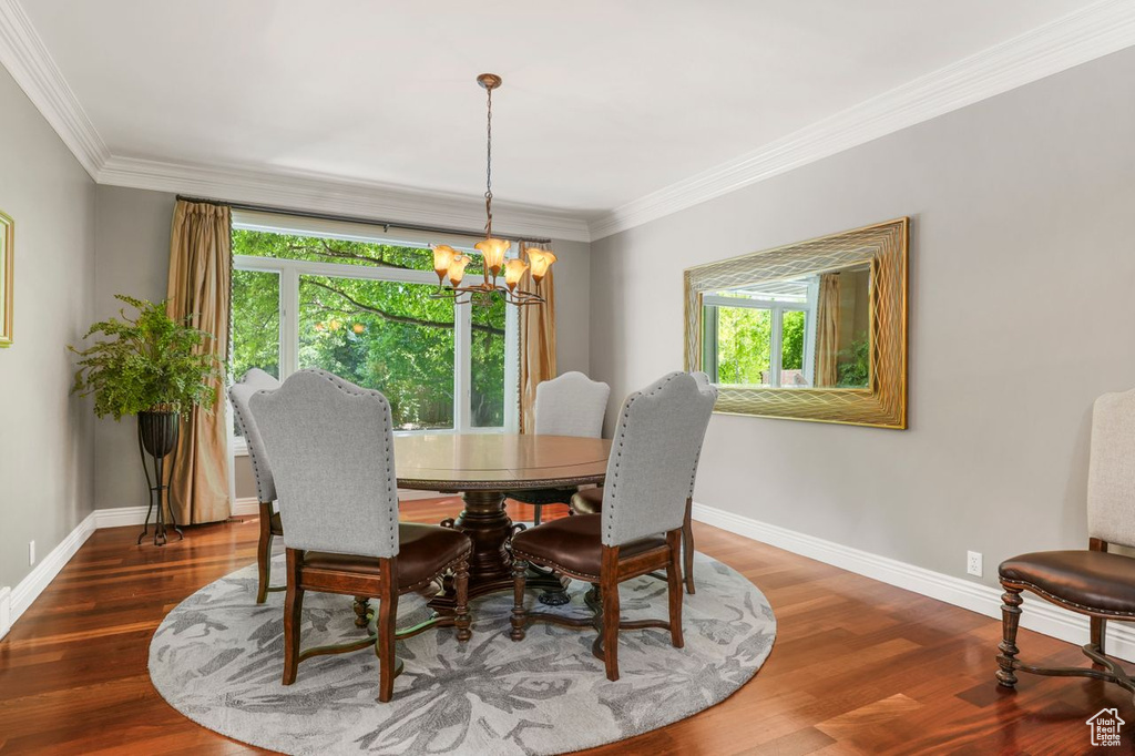 Dining space with an inviting chandelier, dark hardwood / wood-style floors, and ornamental molding