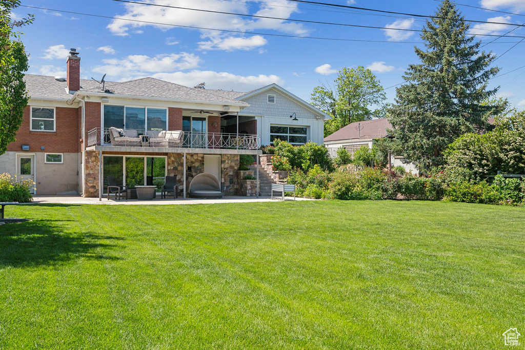 Rear view of house with ceiling fan, a patio, stairway, a lawn, and a chimney