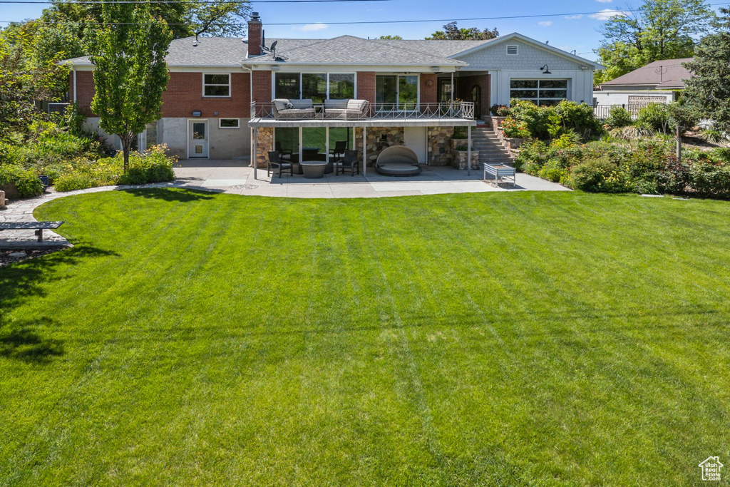 Rear view of house featuring a patio area, stairs, a chimney, a yard, and brick siding