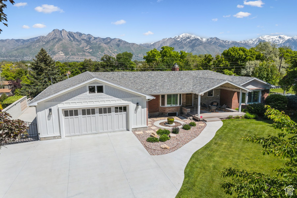 Ranch-style house featuring a porch, a front yard, concrete driveway, a garage, and a chimney
