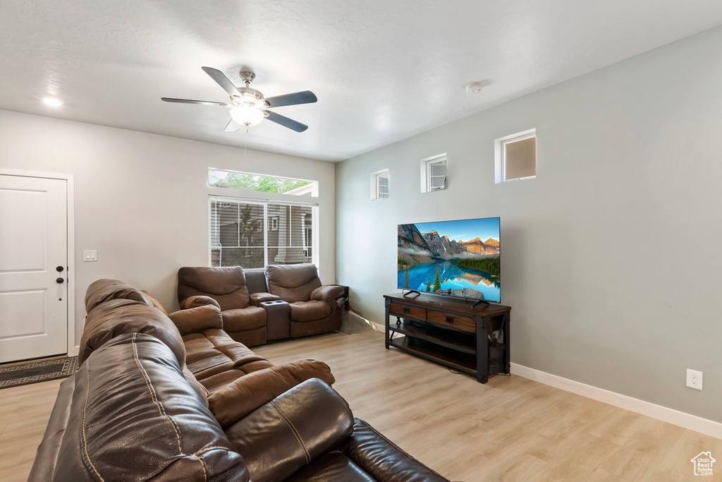 Living area featuring a ceiling fan, light wood finished floors, and baseboards