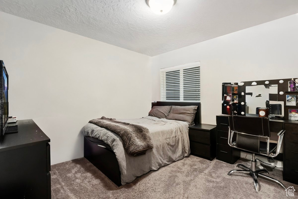 Bedroom featuring light carpet, a desk, and a textured ceiling