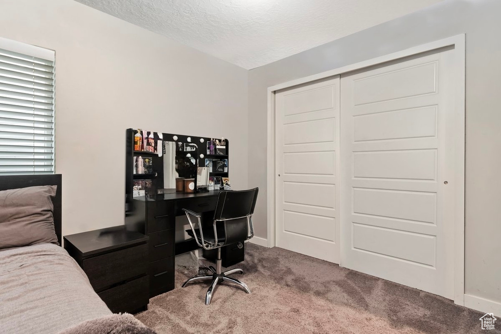 Bedroom with carpet, a textured ceiling, an office area, a closet, and baseboards