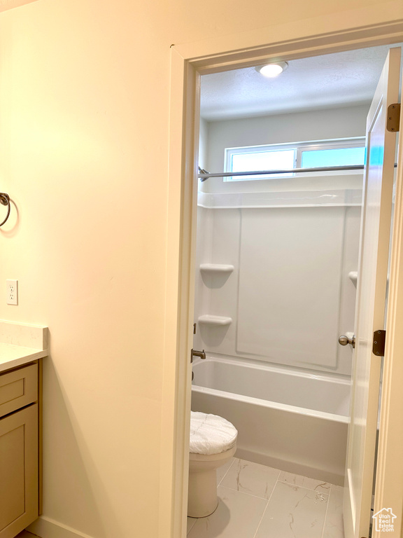 Full bathroom with tub / shower combination, baseboards, toilet, marble finish floor, and vanity