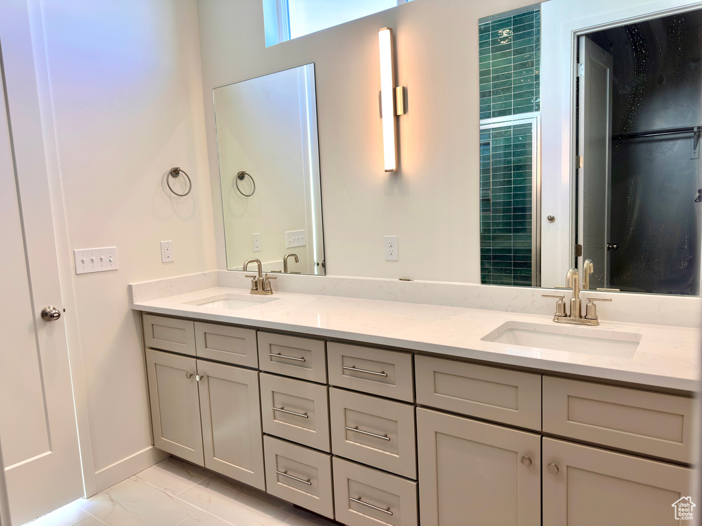 Bathroom featuring double vanity, baseboards, marble finish floor, and a sink