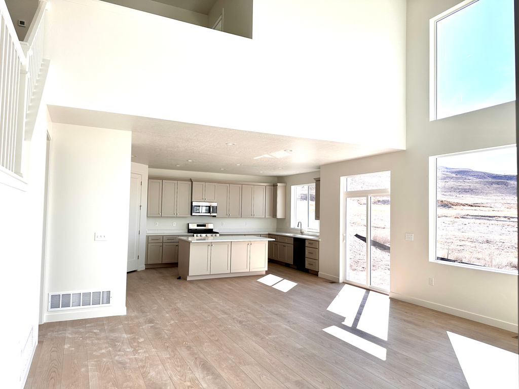 Kitchen featuring visible vents, a kitchen island, stainless steel appliances, light countertops, and a towering ceiling