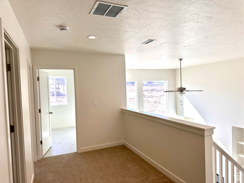 Corridor with visible vents, an upstairs landing, baseboards, and carpet flooring