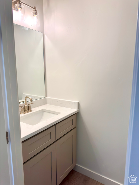 Bathroom with vanity, wood finished floors, and baseboards