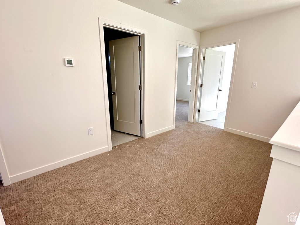 Empty room with light colored carpet and baseboards