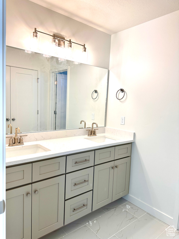 Full bathroom with a sink, baseboards, marble finish floor, and double vanity