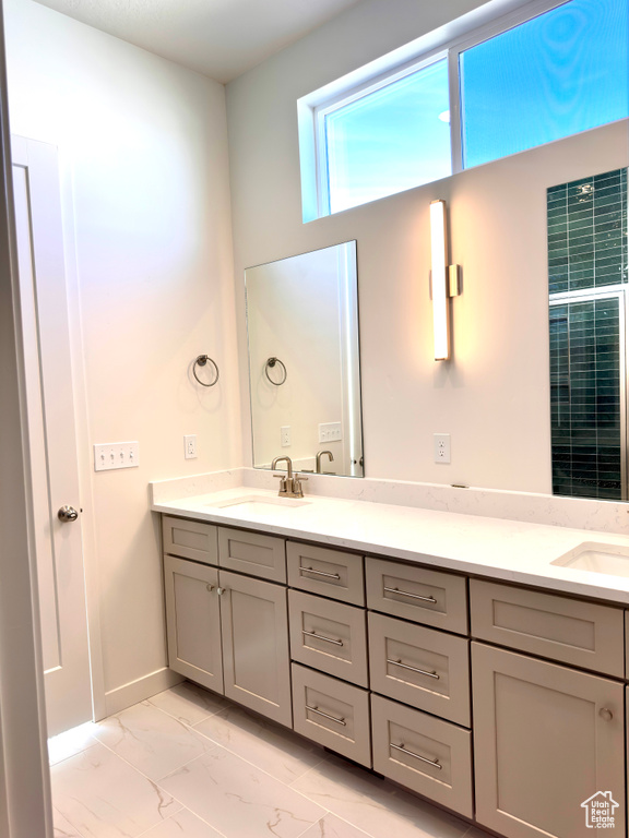 Full bath featuring double vanity, baseboards, marble finish floor, and a sink