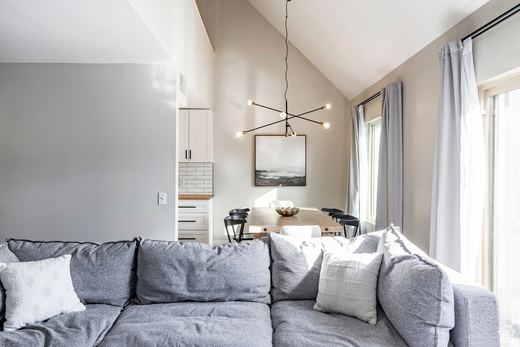 Living room with plenty of natural light, a chandelier, and lofted ceiling