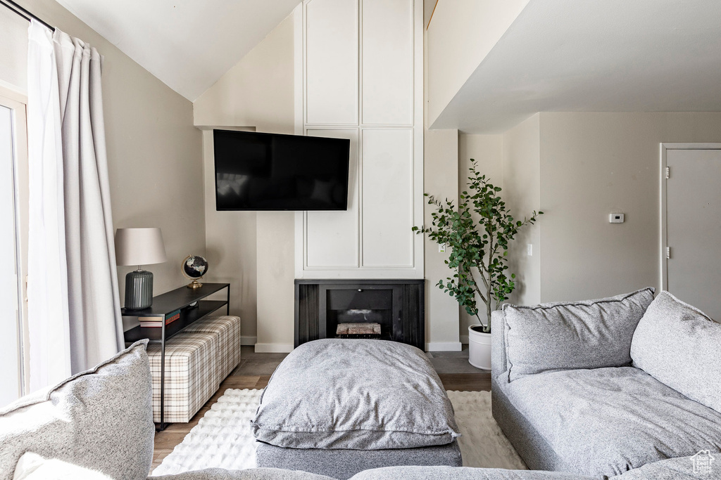 Living area featuring baseboards, wood finished floors, a fireplace, and vaulted ceiling