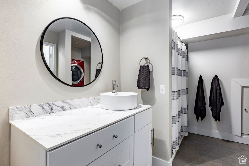 Bathroom with curtained shower, baseboards, washer / dryer, wood finished floors, and vanity