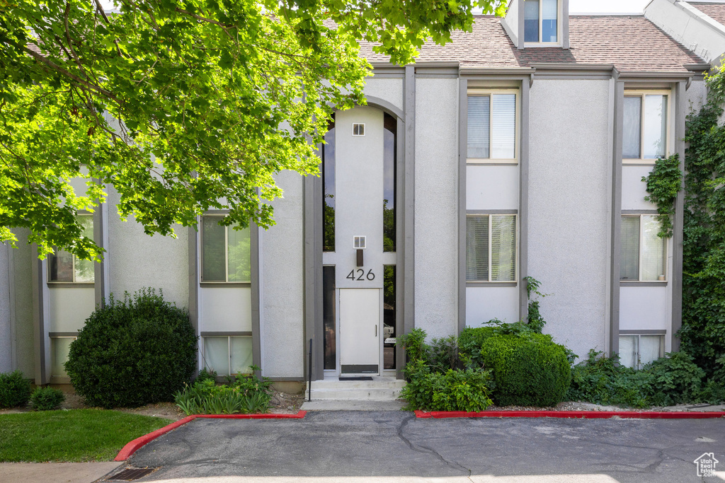 View of front of home featuring stucco siding and a shingled roof