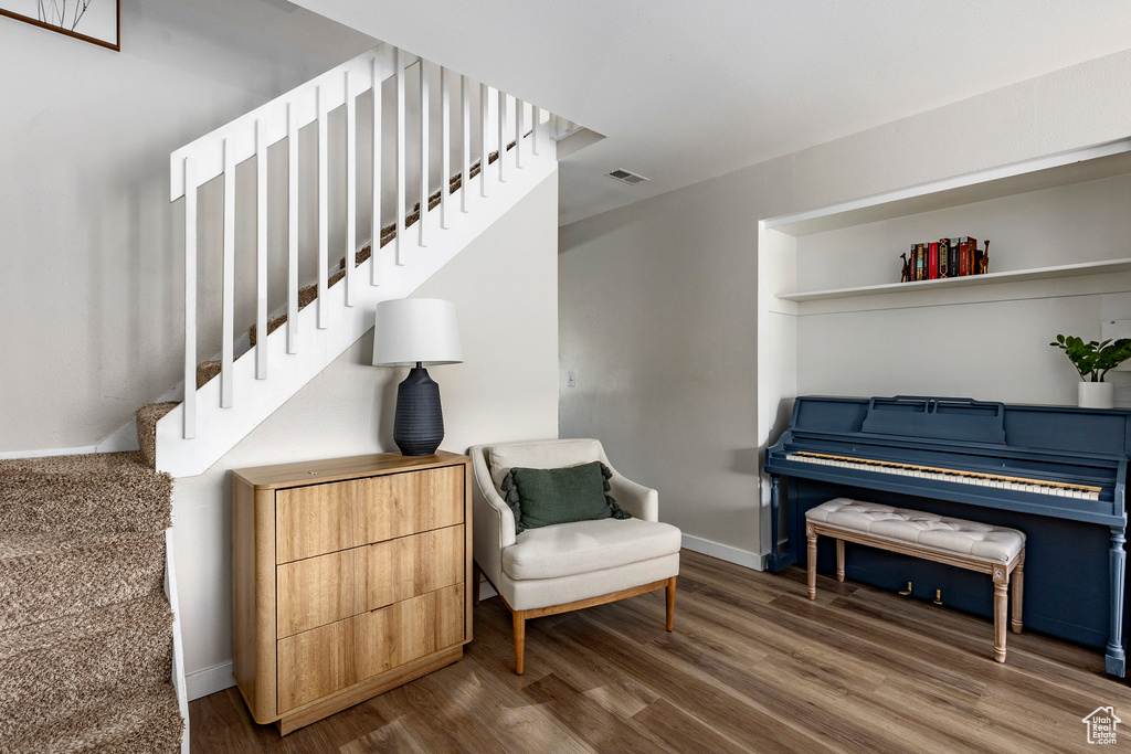 Sitting room with stairs, wood finished floors, visible vents, and baseboards