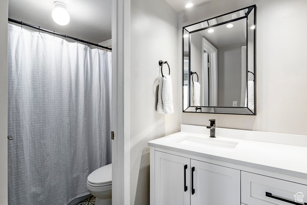 Bathroom featuring a shower with shower curtain, toilet, and vanity