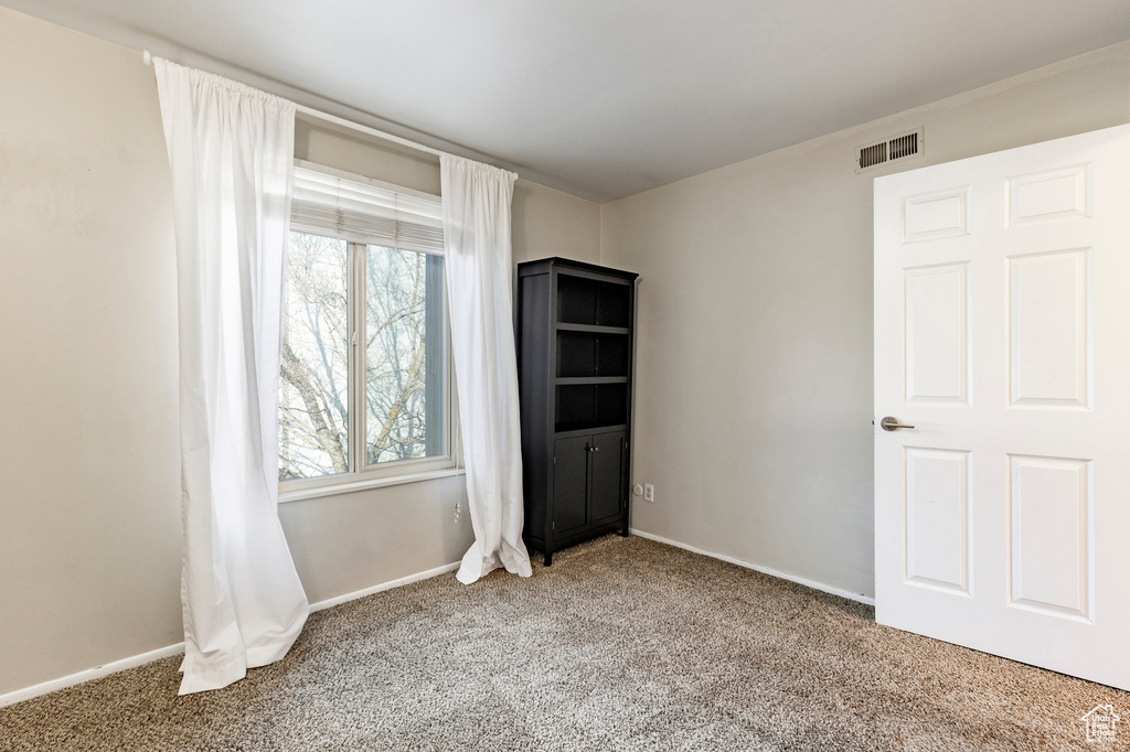 Carpeted spare room featuring visible vents and baseboards