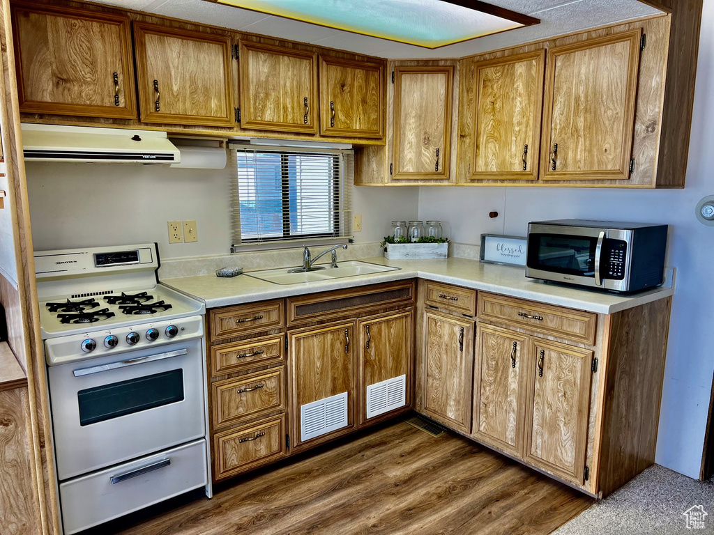 Kitchen with sink, gas range oven, and dark hardwood / wood-style floors