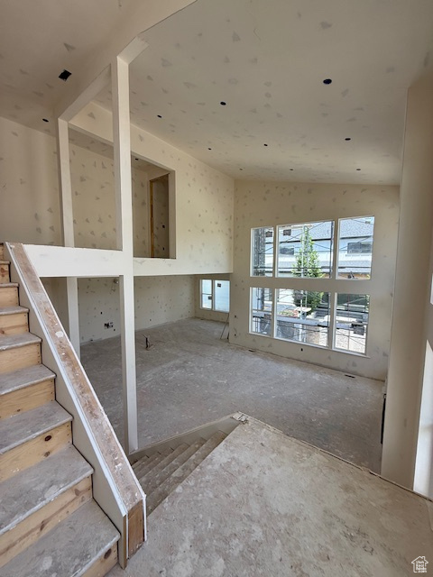 Unfurnished living room featuring plenty of natural light and stairway
