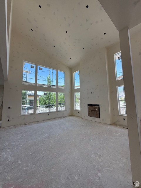 Unfurnished living room with a high ceiling and a fireplace