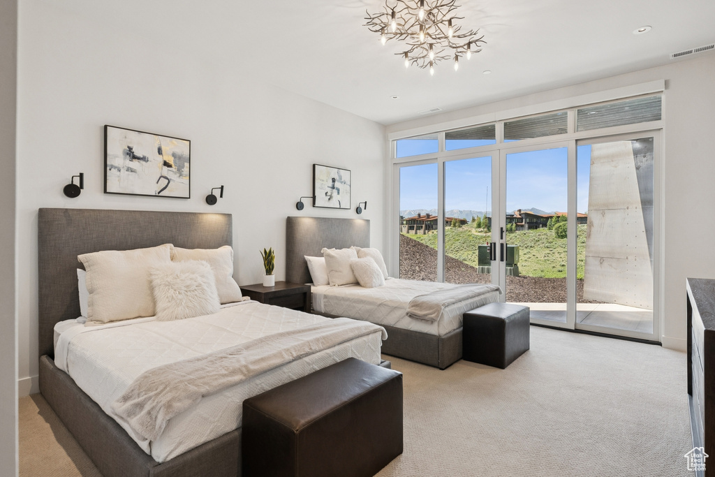 Bedroom featuring access to exterior, a chandelier, and light carpet