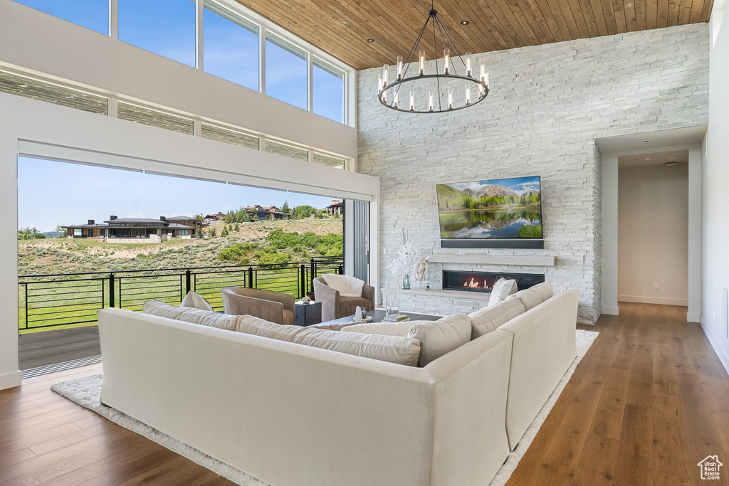 Living area featuring a high ceiling, wood ceiling, a fireplace, a chandelier, and wood finished floors