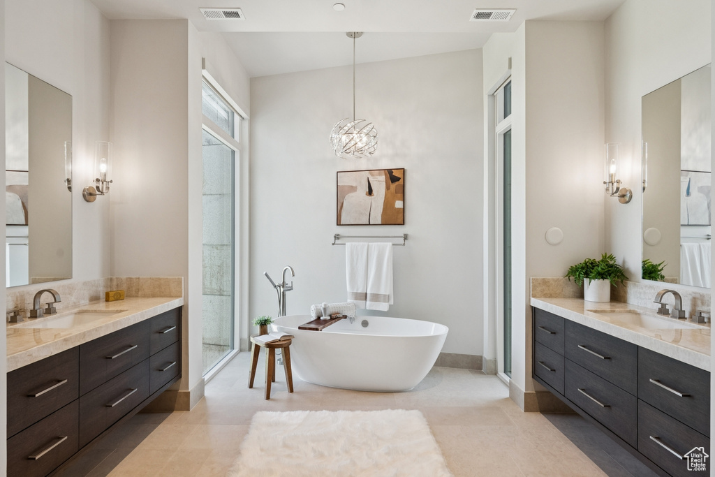 Bathroom featuring two vanities, a freestanding tub, and tile patterned flooring