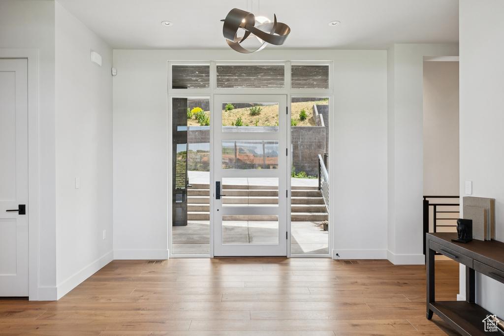 Doorway with light wood-type flooring, recessed lighting, and a chandelier