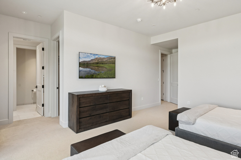 Bedroom featuring light colored carpet, ensuite bathroom, and a chandelier