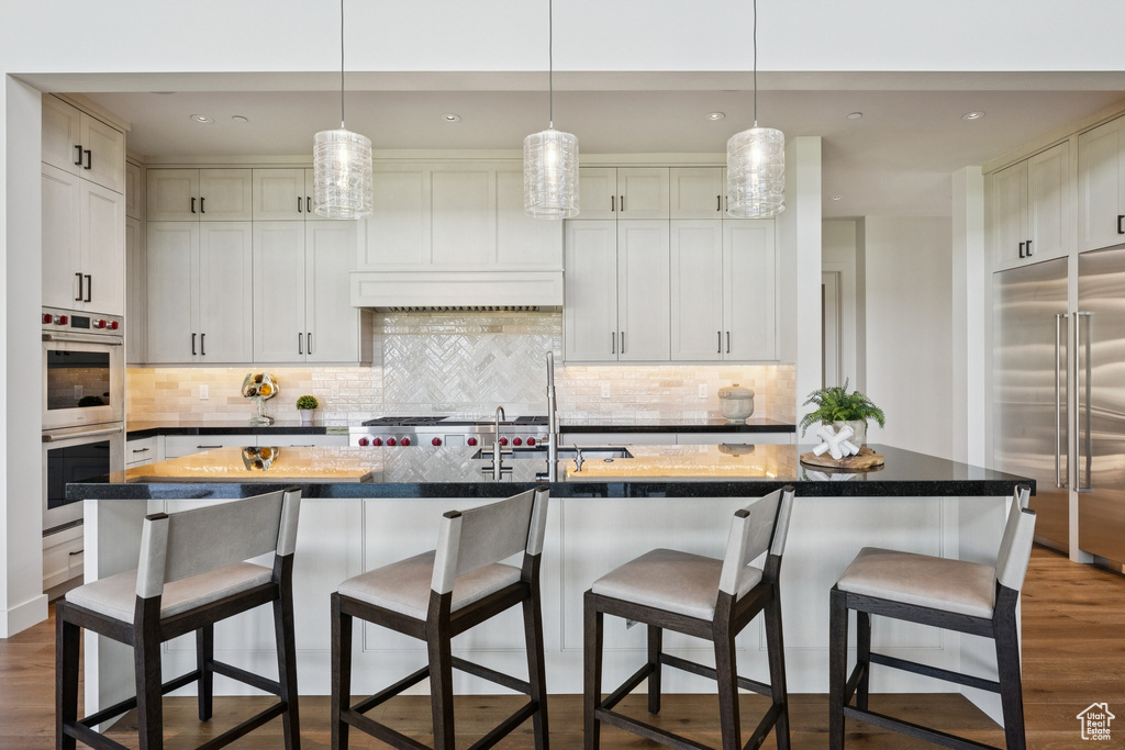 Kitchen with stainless steel appliances, dark wood-style floors, decorative backsplash, and recessed lighting
