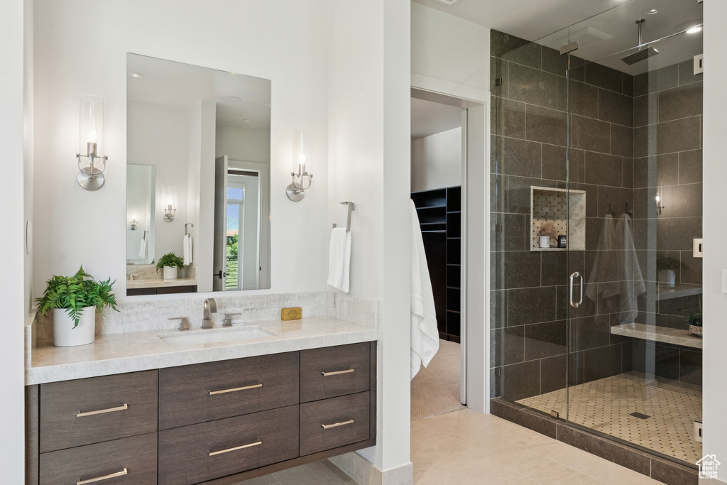 Bathroom with a stall shower, vanity, a walk in closet, tasteful backsplash, and tile patterned flooring