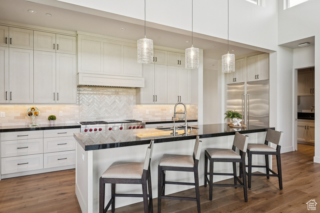 Kitchen with built in refrigerator, dark countertops, a breakfast bar area, dark wood-type flooring, and recessed lighting