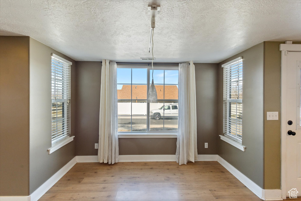 Unfurnished dining area featuring light wood-type flooring, plenty of natural light, and baseboards