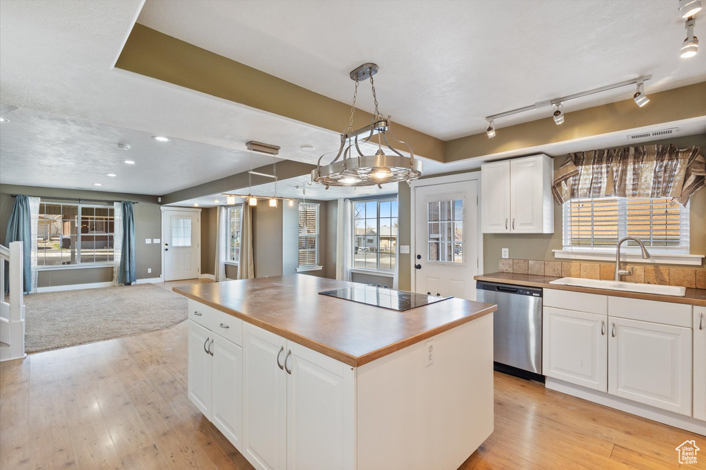 Kitchen with black electric stovetop, open floor plan, a sink, light wood-type flooring, and dishwasher