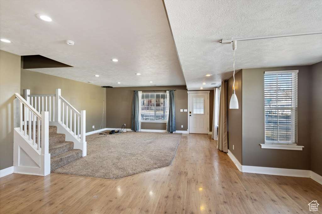 Foyer featuring a textured ceiling, baseboards, wood finished floors, and a healthy amount of sunlight