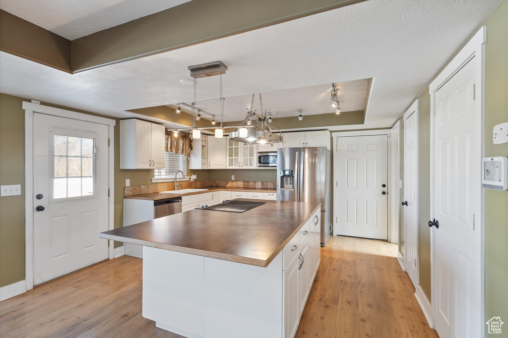 Kitchen featuring light wood-style floors, white cabinetry, stainless steel appliances, and a sink