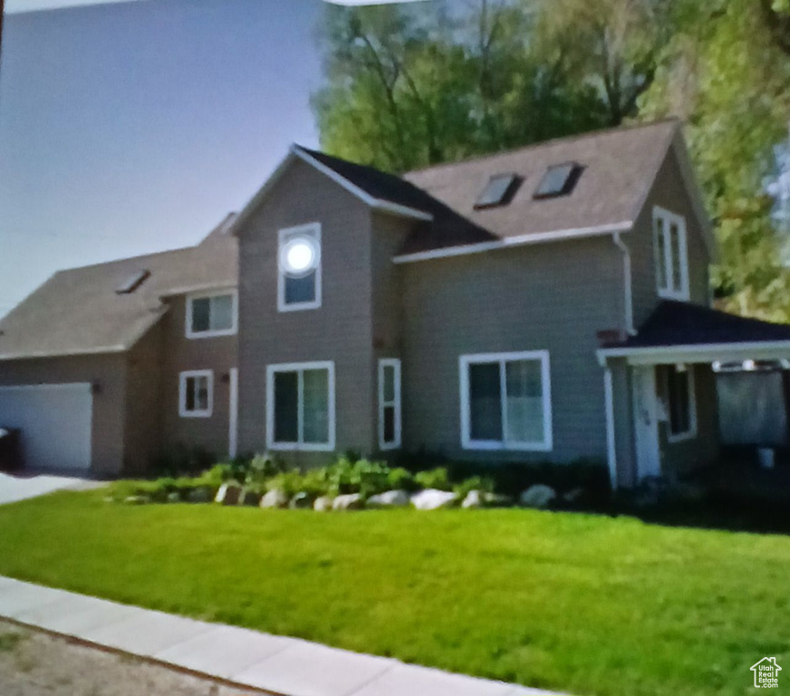 View of front of property with a front yard and a garage