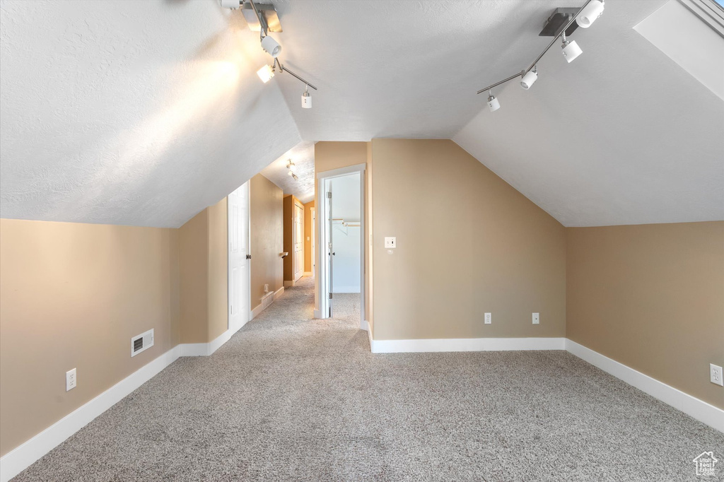 Bonus room featuring visible vents, baseboards, lofted ceiling, a textured ceiling, and carpet flooring