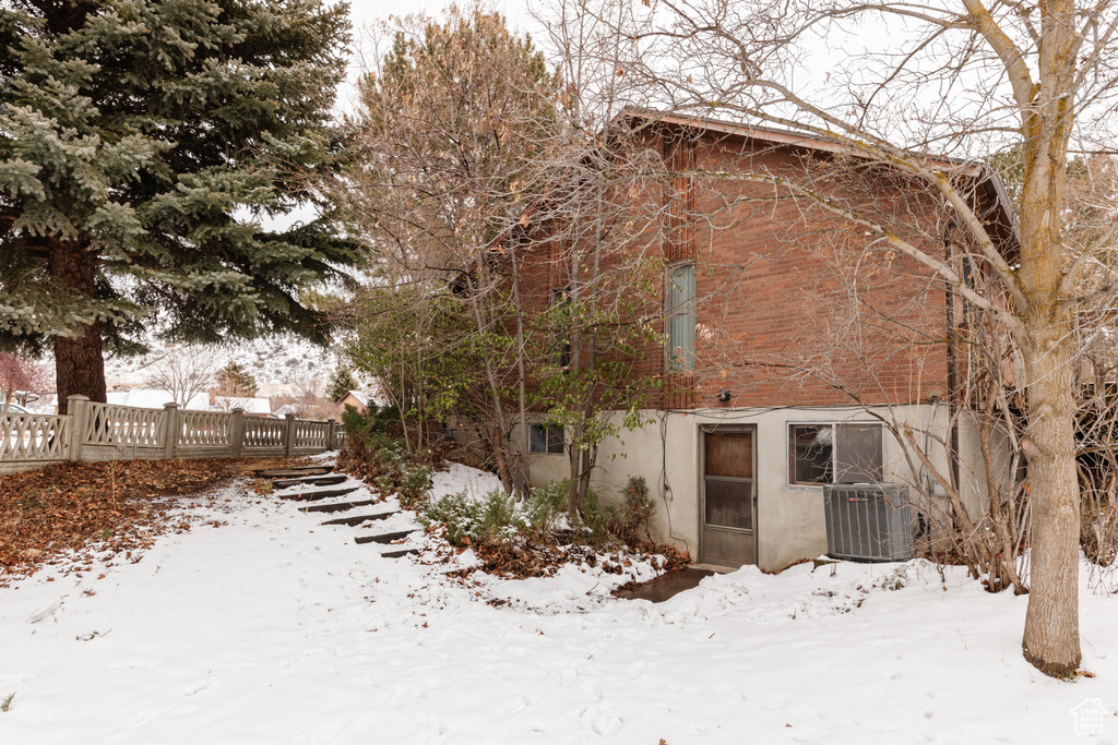 Snow covered back of property with central AC