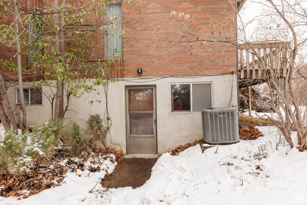 Snow covered property entrance with central AC unit