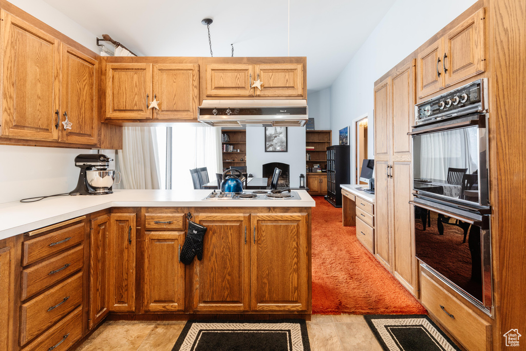 Kitchen with double oven, kitchen peninsula, exhaust hood, and white gas stovetop