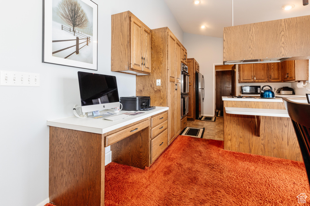 Kitchen featuring kitchen peninsula, stainless steel refrigerator, a breakfast bar area, and multiple ovens