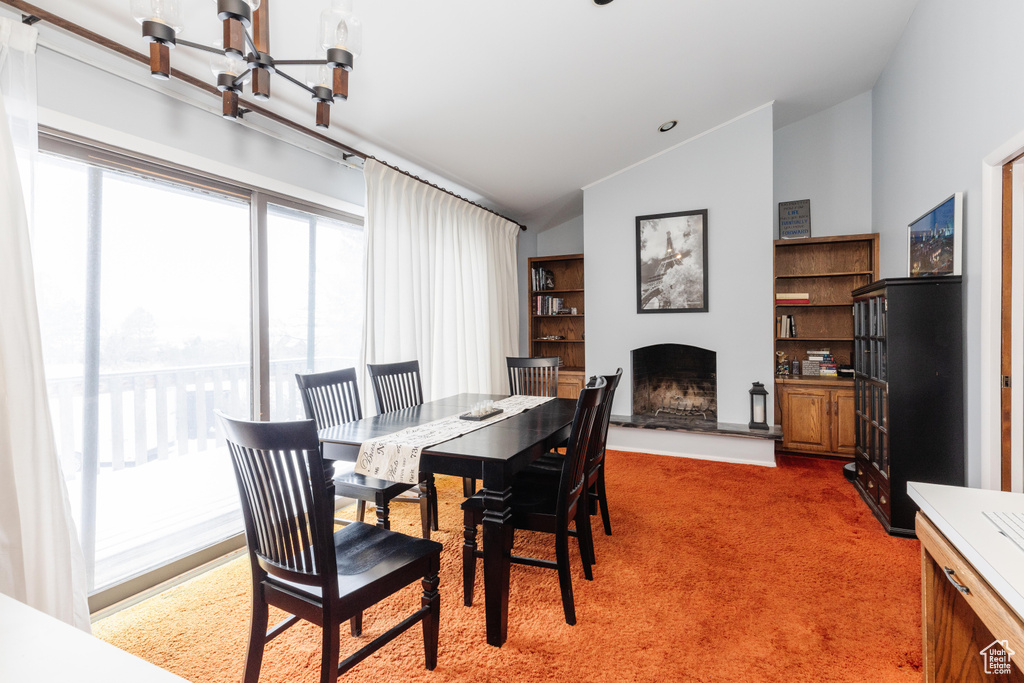 Carpeted dining space with a chandelier and lofted ceiling