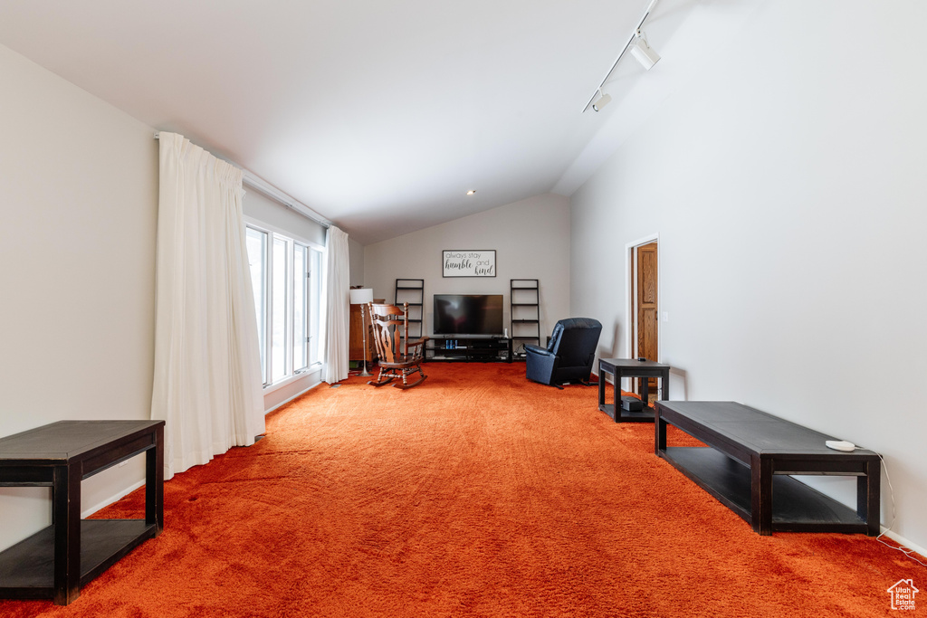 Interior space with track lighting, vaulted ceiling, and carpet flooring