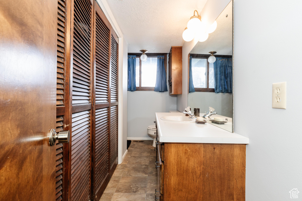 Bathroom with toilet, a textured ceiling, and vanity