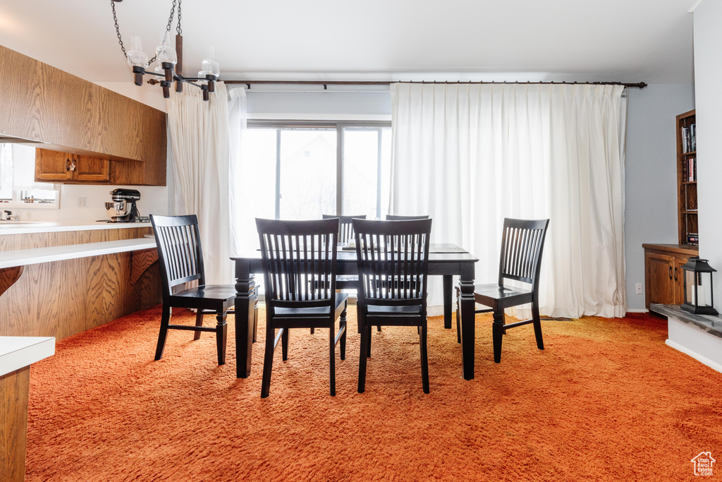 Carpeted dining space with an inviting chandelier