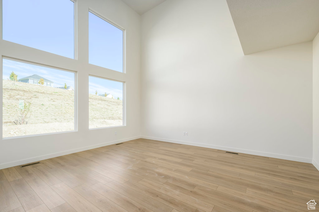 Spare room with light hardwood / wood-style floors and a towering ceiling