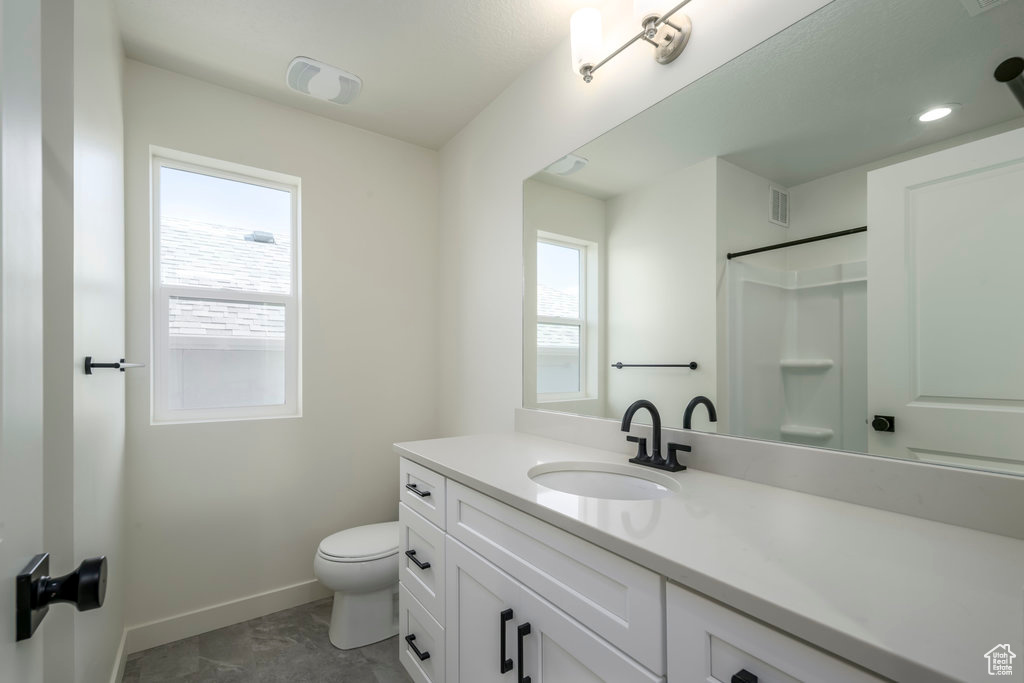Bathroom featuring toilet, vanity, and walk in shower