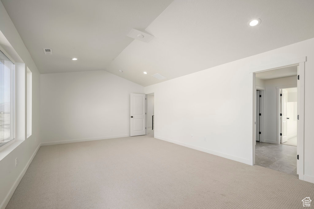 Carpeted empty room with vaulted ceiling